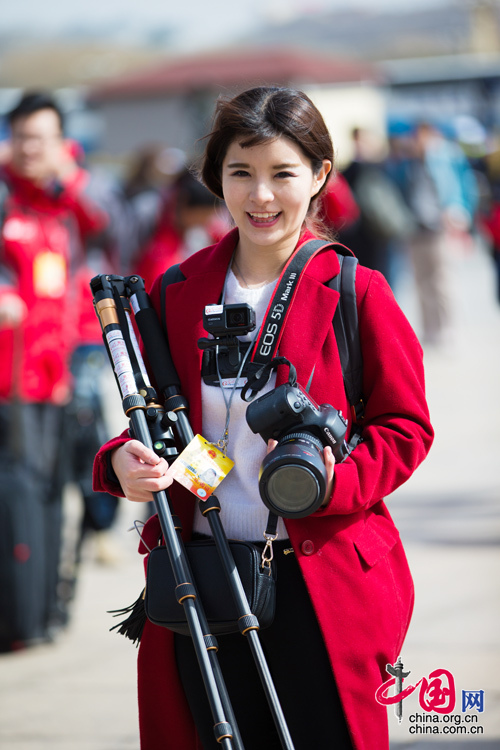 2016年兩會(huì)，人民大會(huì)大堂前，一位笑容燦爛的紅衣女記者正步入大會(huì)堂。中國(guó)網(wǎng) 鄭亮 攝